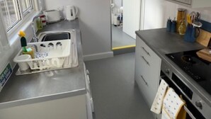 Pieni, käytännöllinen keittiö, jossa on pesuallas, liesi ja kaapit.
