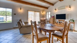 Un amplio salón con una mesa de comedor de madera, un sofá de cuero y sillas de madera.
