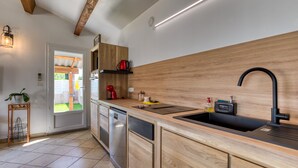 Una cocina moderna con armarios de madera, un lavamanos negro y un lavavajillas empotrado.