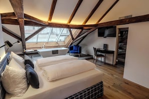 A loft bedroom with a skylight, a desk, and a chair.