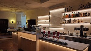 A bar area with a wooden counter, shelves with bottles, and a coffee machine. - Goldener Engl (Hall In Tirol)
