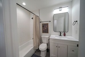 Une salle de bain avec une baignoire blanche, des toilettes et un lavabo.
