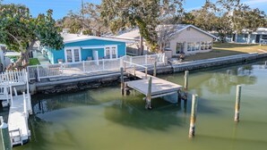 Une propriété située au bord de l’eau, dotée d’un quai, d’un petit bâtiment à la façade bleue et d’une zone herbeuse.