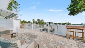 A patio with wicker furniture, a white fence, and a view of the water. - Waterfront Modern Condo | Pet Friendly near Beach! (Indian Rocks Beach)