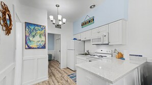 A modern kitchen with white cabinetry, a central island, a microwave, and a stove. - Waterfront Modern Condo | Pet Friendly near Beach! (Indian Rocks Beach)