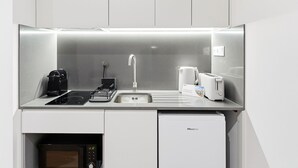 Une cuisine compacte équipée d’un évier, d’une machine à café, d’un grille-pain et d’un petit réfrigérateur.