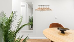Un espace repas moderne avec une table en bois, une seule chaise et un porte-vêtements en bois suspendu.