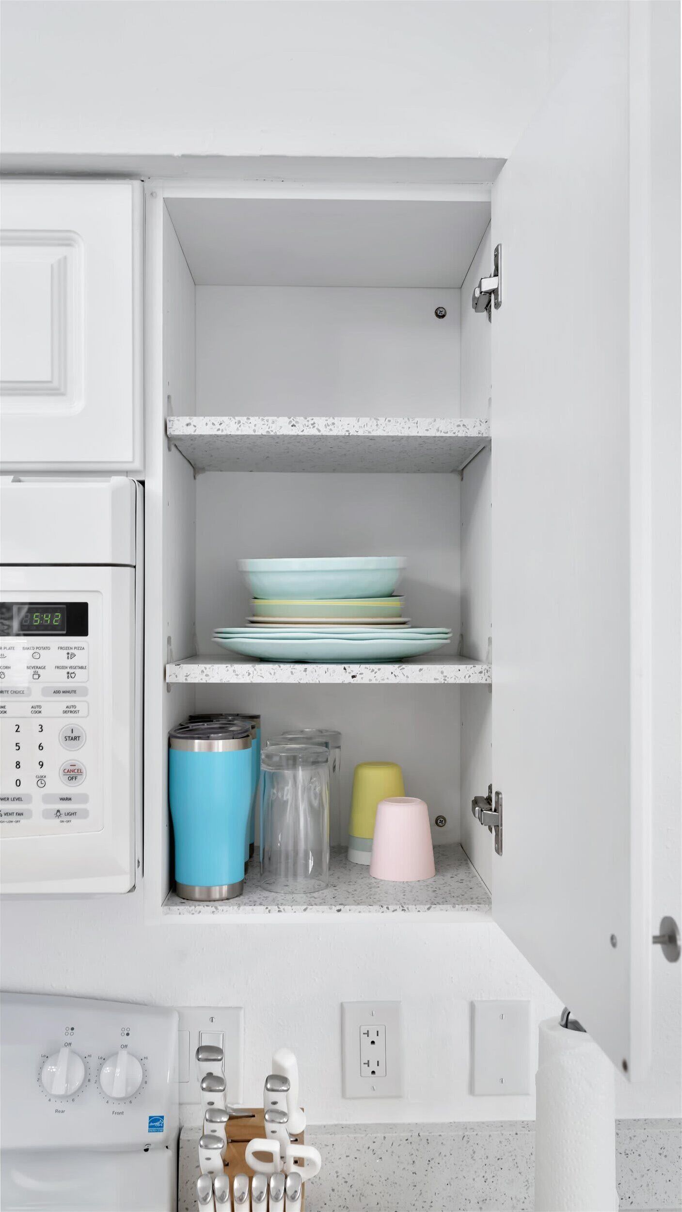 A kitchen with a microwave, a coffee maker, and a kettle on the counter.