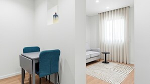 A modern living room with a grey sofa, a small round table, and a patterned rug. - GuestReady The 7 Seas - Caspian Sea 1E (Porto)