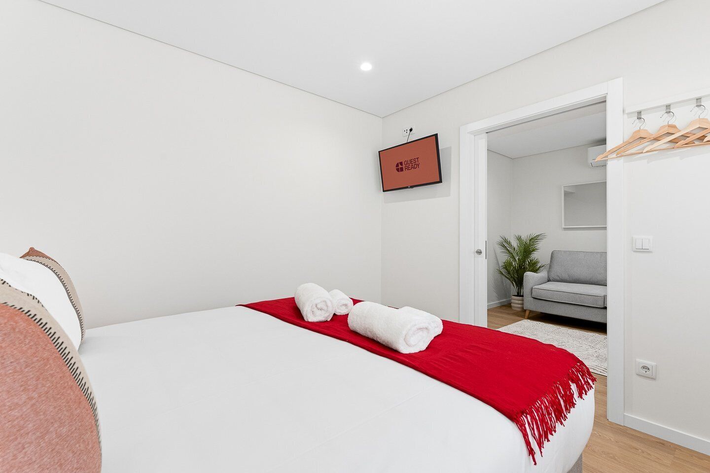 Une chambre d’hôtel moderne avec un grand lit, un plaid rouge et un panneau indiquant que la chambre est prête à accueillir les clients.