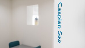 A room with a table and two chairs, a window, and the text "Caspian Sea" on the wall. - GuestReady The 7 Seas - Caspian Sea 1E (Porto)
