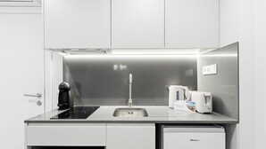 Et kompakt tekøkken med indbygget komfur, vask og lille køleskab.