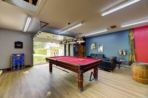 A pool table in a room with a blue wall, a red accent wall, and a wooden floor.