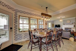 A dining area with a large table and chairs, a chandelier, and a fireplace.