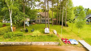Una casa con terraza, zona de juegos techada y un muelle con kayaks.