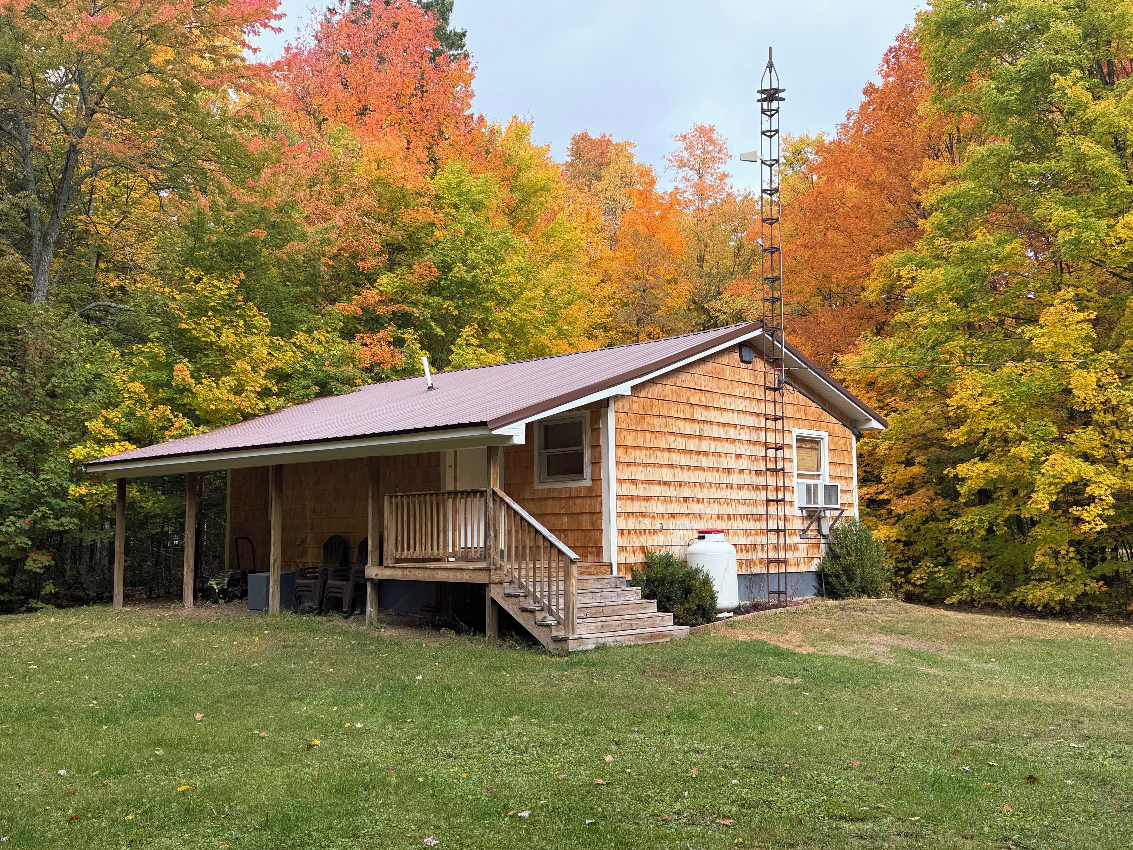 A wooden cabin with a porch, a staircase, and a satellite dish.