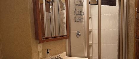 Un baño con tocador, lavabo, espejo y cabina de ducha.