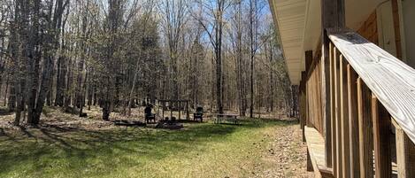 A wooden deck with a view of a forested area and a picnic table.