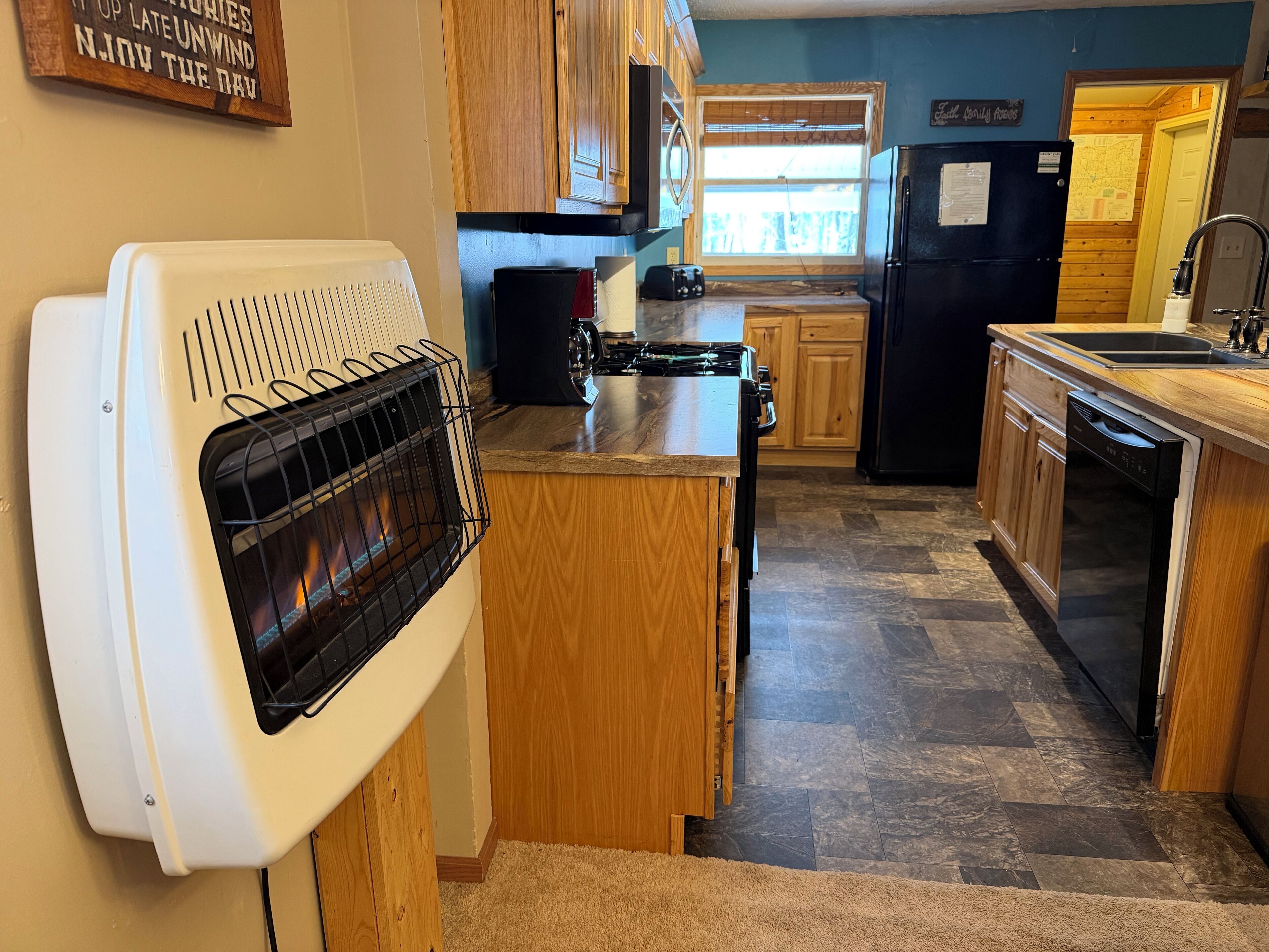 Une cuisine compacte avec des meubles en bois, une cuisinière encastrée, un réfrigérateur noir et un lave-vaisselle.