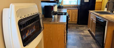 Une cuisine compacte avec des meubles en bois, une cuisinière encastrée, un réfrigérateur noir et un lave-vaisselle.