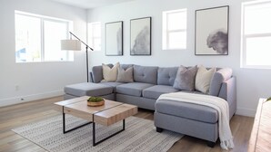 Un salon moderne avec un canapé d’angle gris, une table basse en bois et un lampadaire.