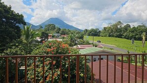 A view from a balcony overlooking a residential area with a mountain in the background. - Modern Aparm with Private Jacuzzi •Arenal Volcano View • 3 Minutes from Downtown (La Fortuna)