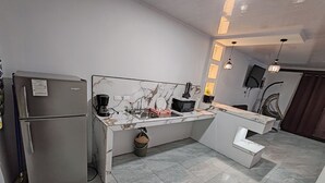 A modern kitchen with a built-in refrigerator, a marble backsplash, and a small island with a sink. - Modern Aparm with Private Jacuzzi •Arenal Volcano View • 3 Minutes from Downtown (La Fortuna)