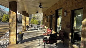 Eine Terrasse im Freien mit Steinsäulen, Deckenventilatoren und Sitzgelegenheiten.