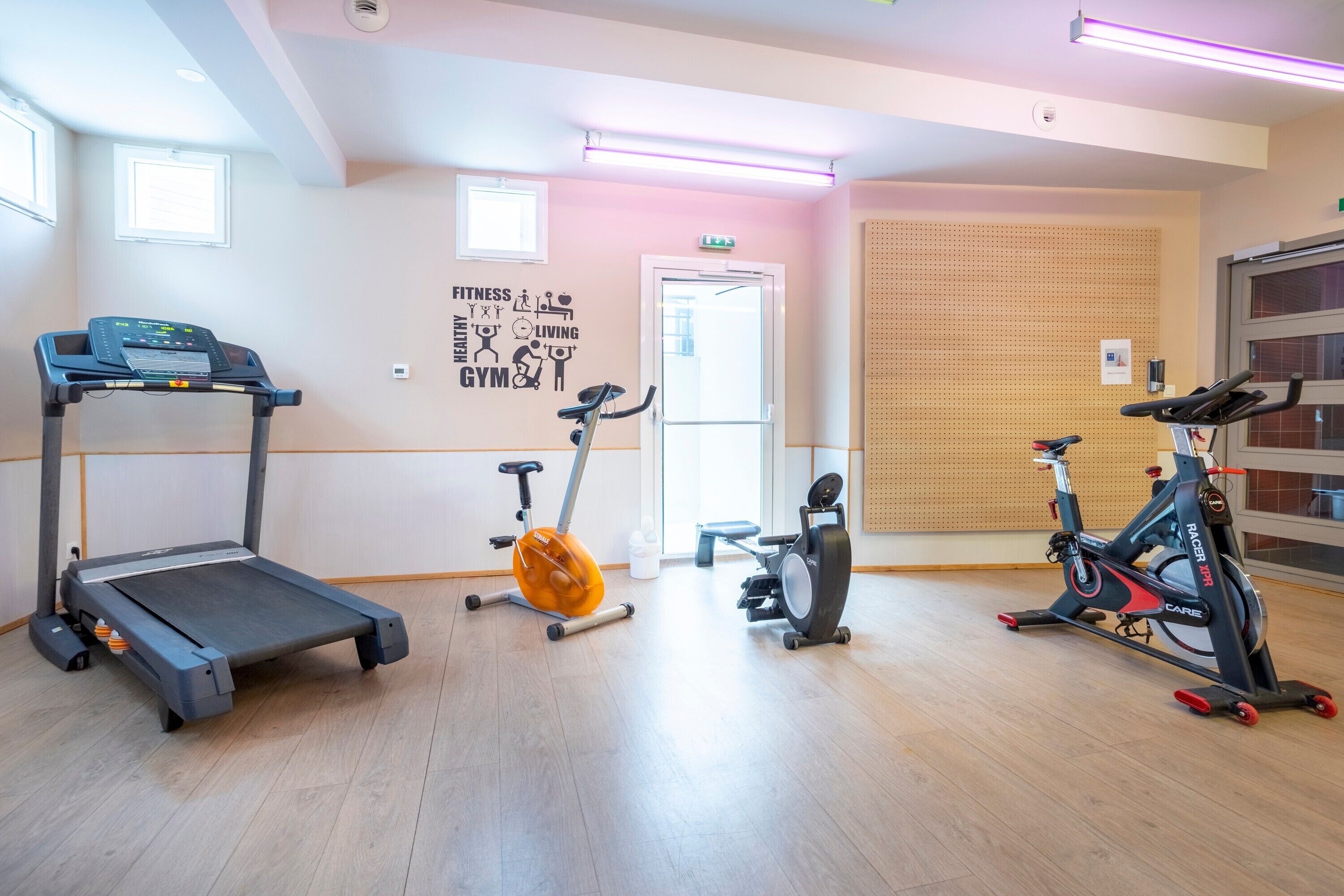 Une salle de sport équipée d’un tapis de course, d’un vélo d’appartement et d’un appareil elliptique.