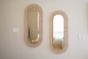 Two oval mirrors with a woven frame on a plain wall. - New front beach apartment with golf cart (Puerto Morelos)