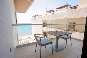 A balcony with a table and chairs overlooking a beach. - New front beach apartment with golf cart (Puerto Morelos)