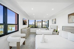 Une chambre d’hôtel moderne dotée d’un grand lit, d’un lit plus petit, d’un coin salon et offrant une vue sur le paysage urbain.
