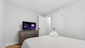 Una habitación de hotel con una cama, un televisor sobre un aparador de madera y una puerta.