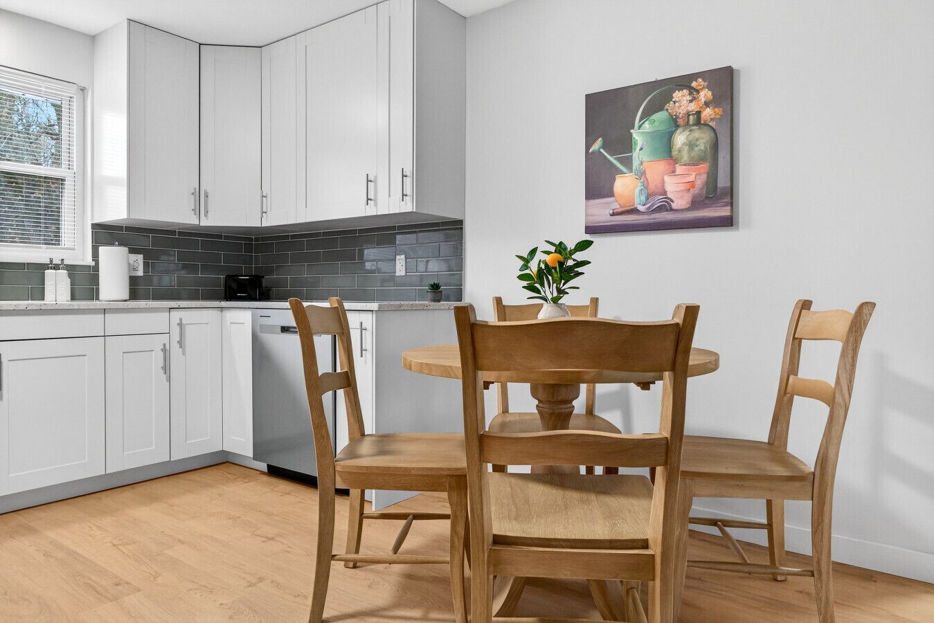A modern kitchen with white cabinets, a black countertop, and a wooden dining table with chairs.