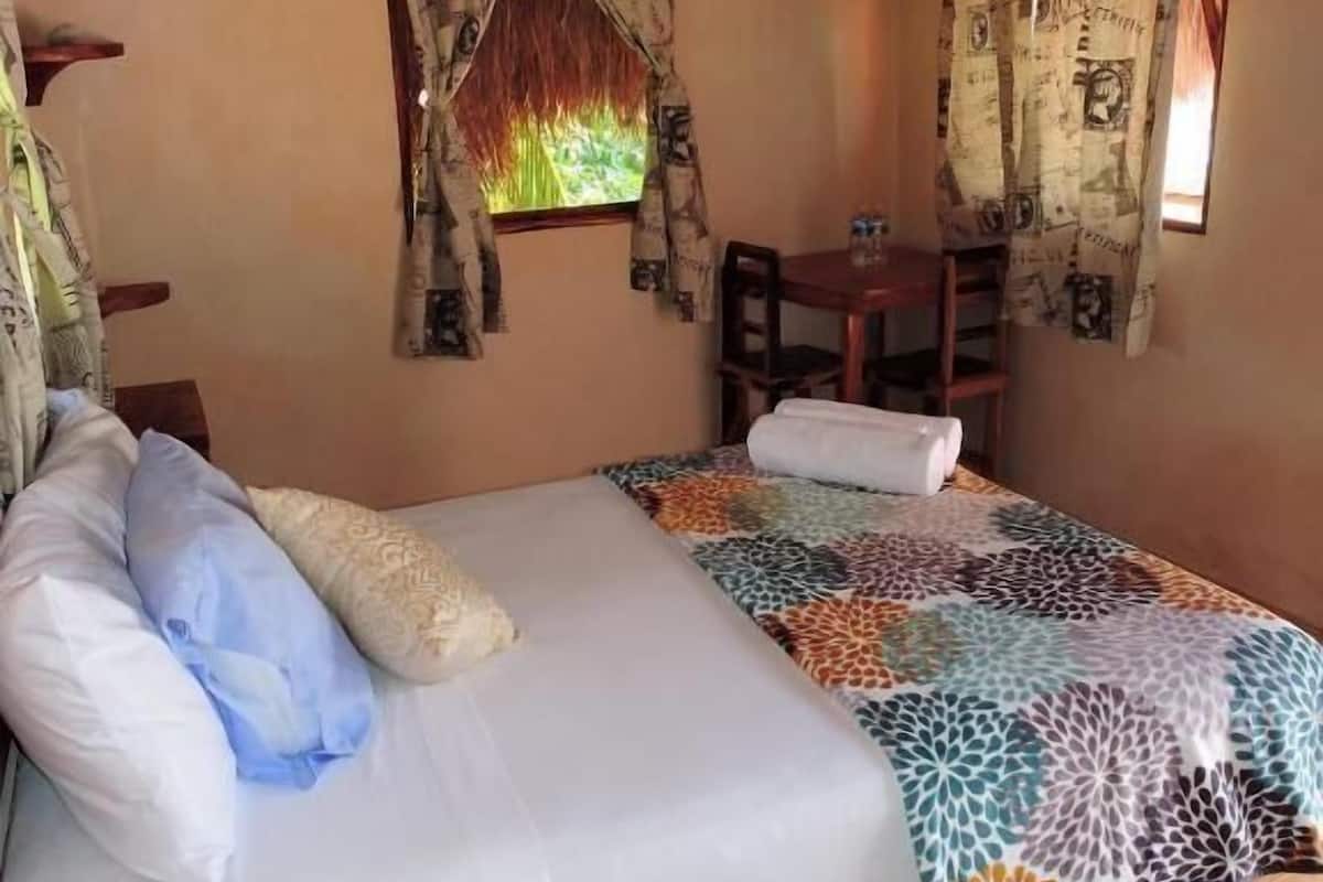 A room with a bed, a small table, and a chair.