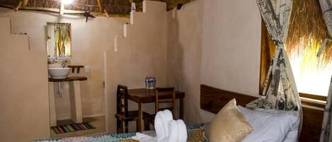 Una habitación con una cama, una mesita, una silla, un lavabo y un espejo.
