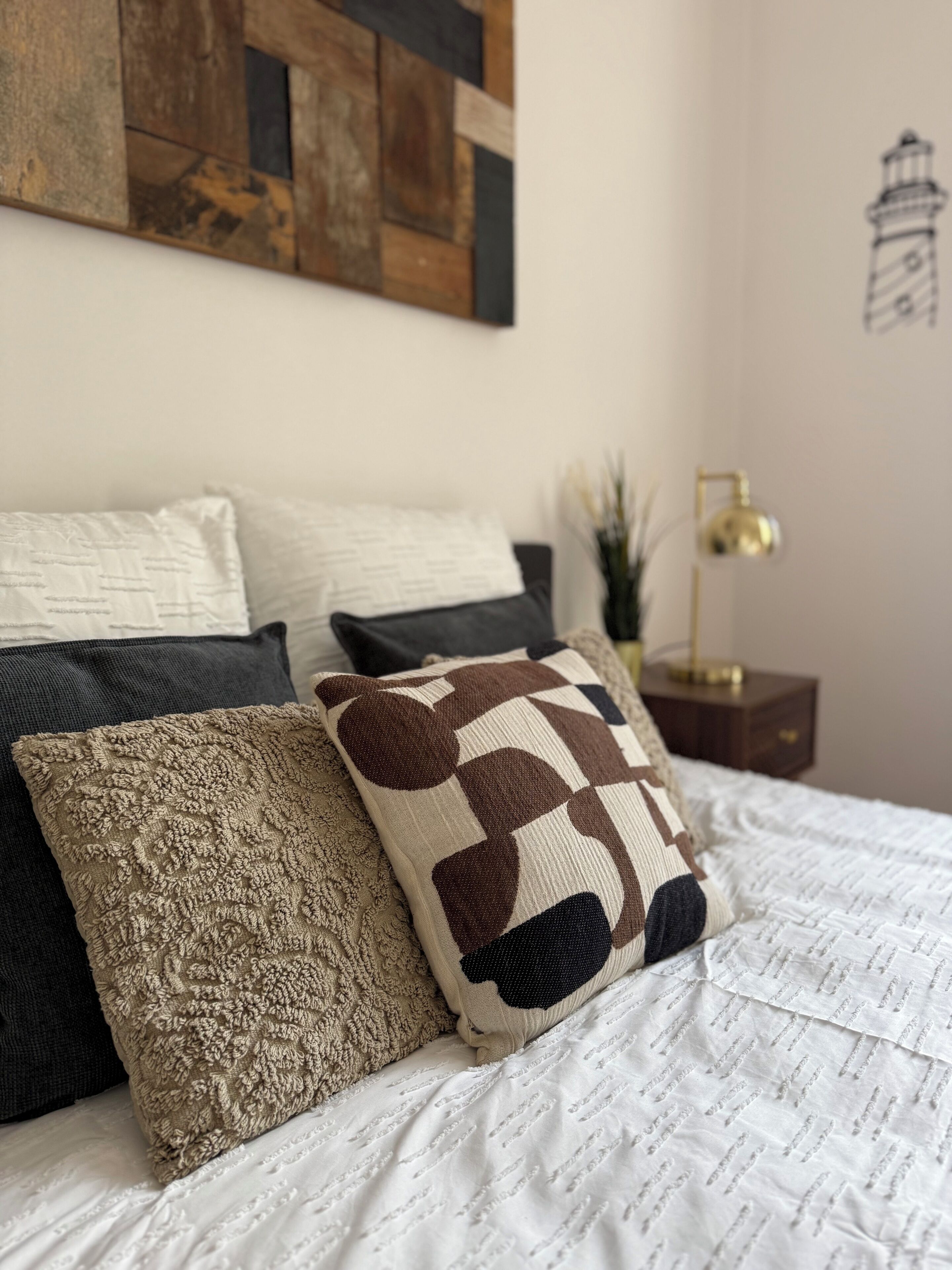 Una cama bien hecha con almohadas estampadas y una colcha blanca.