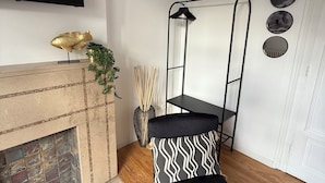 A modern living room with a fireplace, a black metal shelf unit, and a television mounted on the wall. - CHAMBRE LE PHARE (Boulogne-sur-Mer)