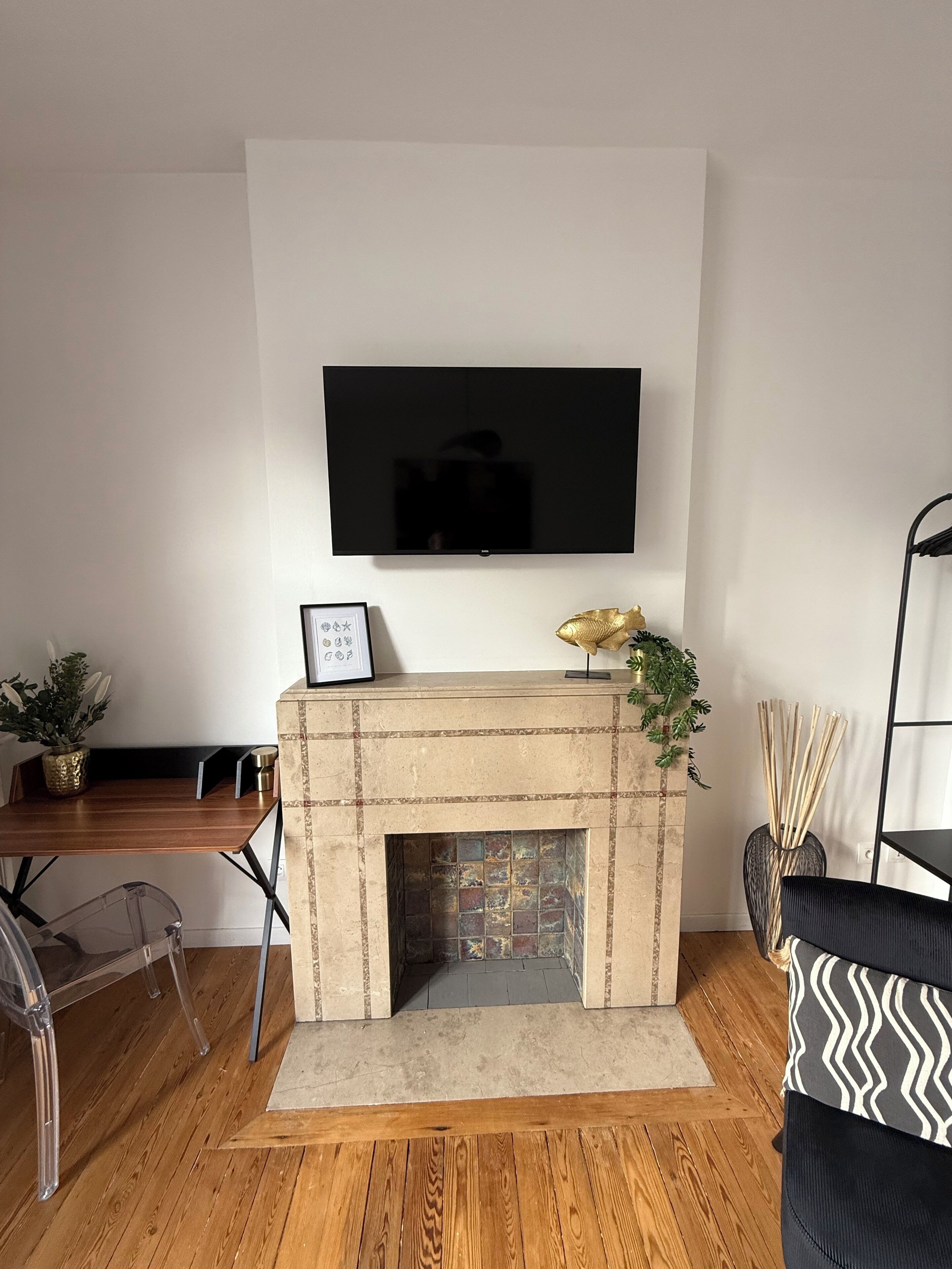 A modern living room with a fireplace, a mounted TV, and a wooden floor.