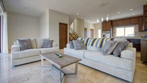 Ein geräumiger Wohnbereich mit zwei Sofas, einem Couchtisch und einer Küche im Hintergrund.