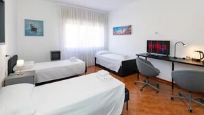 A hotel room with two single beds, a desk with a computer, a chair, a TV, and artwork on the walls. - Double room in Mestre, near Venice, Wi-Fi and self check-in (Venice)