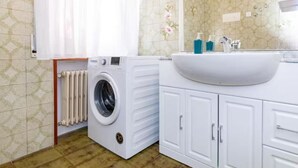 A bathroom with a washing machine, a sink with a mirror, and cabinets. - Double room in Mestre, near Venice, Wi-Fi and self check-in (Venice)