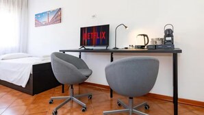 A modern hotel room with a bed, two office chairs, a desk with a computer monitor displaying 'NETFLIX', a lamp, and a kettle. - Double room in Mestre, near Venice, Wi-Fi and self check-in (Venice)