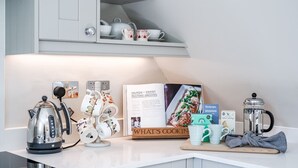 Una cocina con cafetera, teteras, un libro de cocina y una caja para teteras.