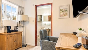 Une pièce avec un bureau en bois, un fauteuil gris, une machine à café et une lampe.