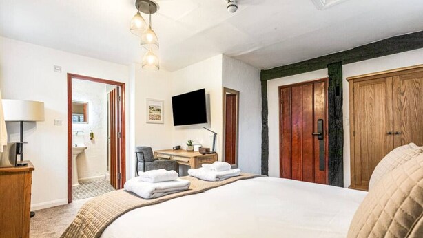 Une chambre d’hôtel avec un grand lit, un bureau avec une chaise, une télévision et des portes en bois.