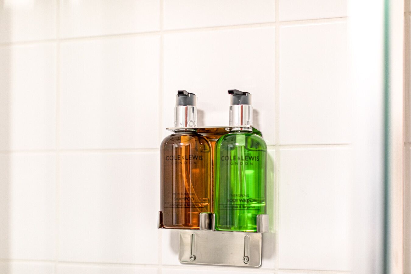 Two bottles of Cole & Lewis shampoo and conditioner mounted on a wall.