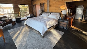 A spacious bedroom with a large bed, a wooden ceiling, and a view of the outdoors. - Stunning, Rustic Cottage on Lake of the Woods! (Kenora)