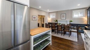 Une cuisine moderne avec un réfrigérateur en acier inoxydable, une table à manger en bois et des chaises.
