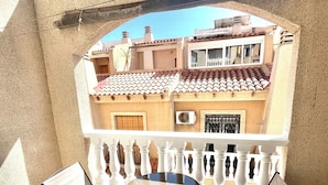 A balcony with a table and chairs, a view of neighboring buildings, and a white railing. - 2BR Apartment Center of Torrevieja (Torrevieja)